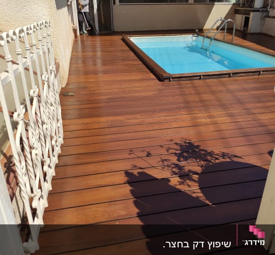 בריכת שחייה על דק עץ עם מעקה מתכת לבן